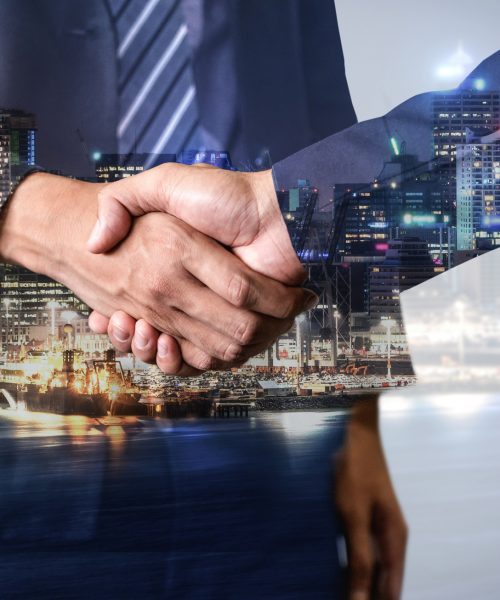 Double exposure image of business people handshake on city office building in background showing partnership success of business deal. Concept of corporate teamwork, trust partner and work agreement.